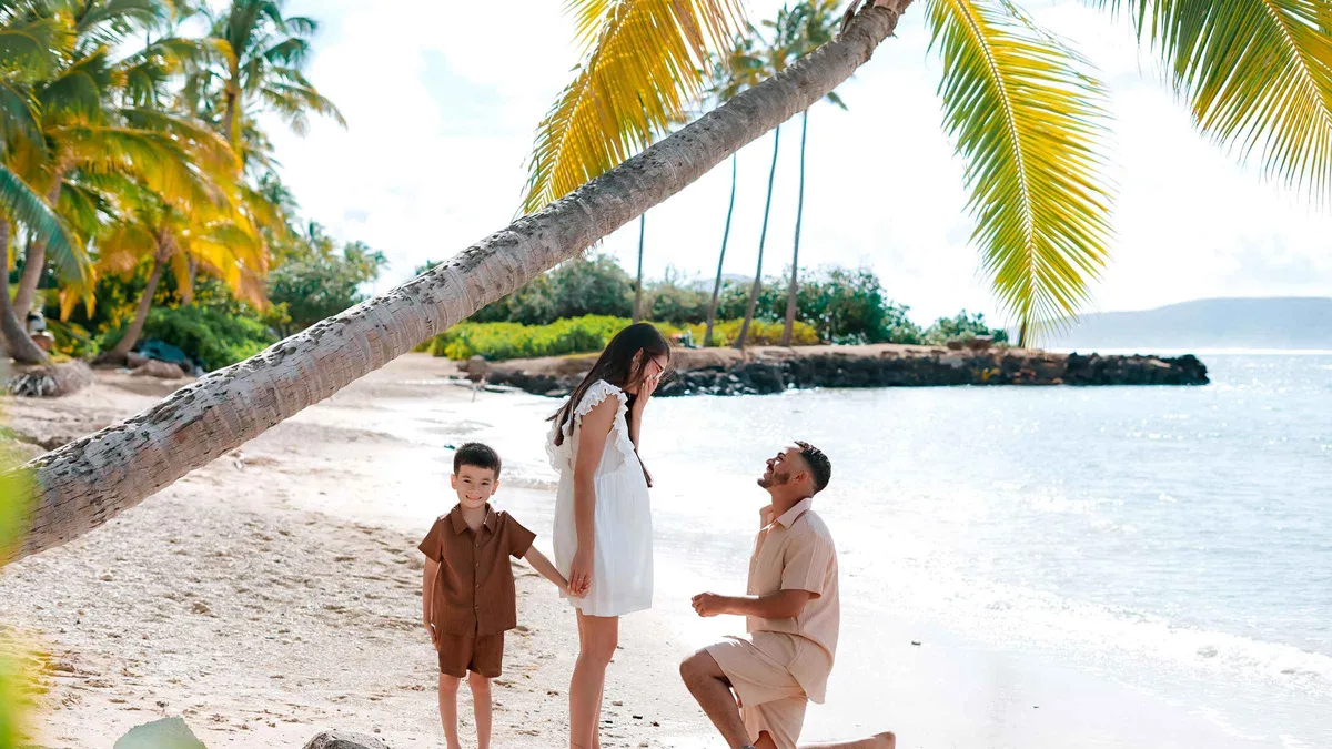 A professional photographer directing a couple at golden hour on a Lahaina beach during a Maui photoshoot in West Maui