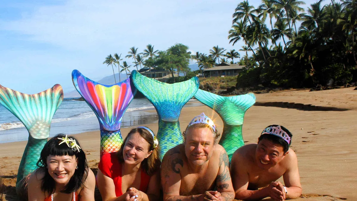 A woman in a swimmable mermaid tail posing in turquoise water during a Maui mermaid photoshoot on a Wailea beach